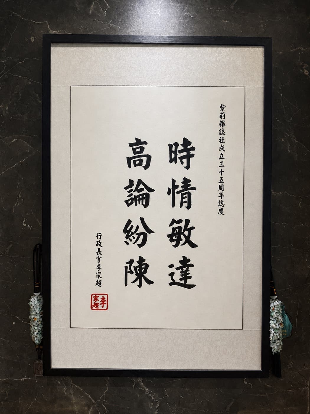本院牆上懸掛的裱框書法作品,寫有「時情敏達 高論紛陳」。上款為「紫荊雜誌社成立三十五周年誌慶」,下款署行政長官李家超並鈐印。此作品為紫荊雜誌社周年誌慶而題,與本院的醫療服務無關。